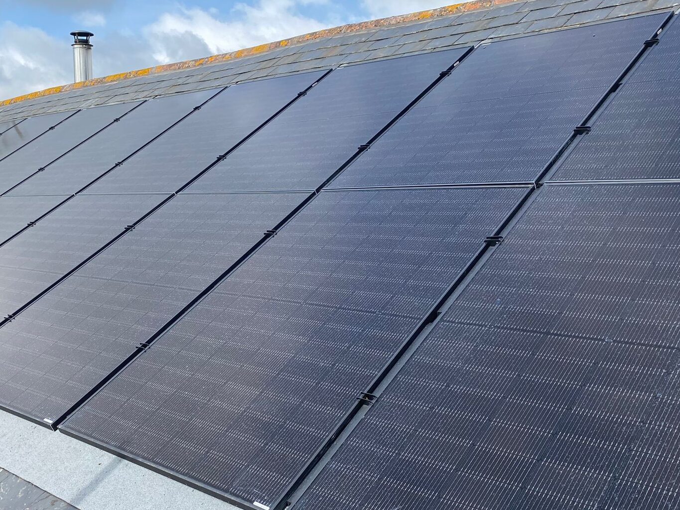 Black solar panels installed in-roof on a slate roof.